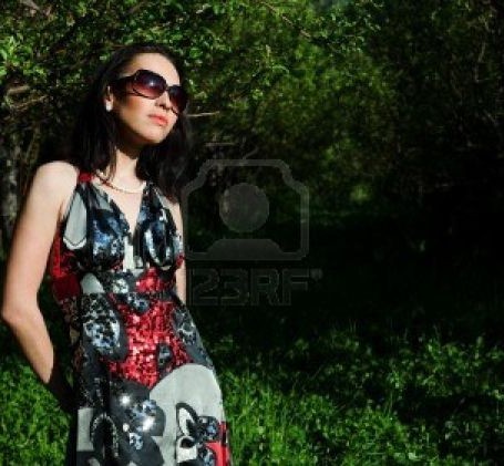 7712494-the-girl-in-a-beautiful-dress-and-sun-glasses-walks-in-a-garden