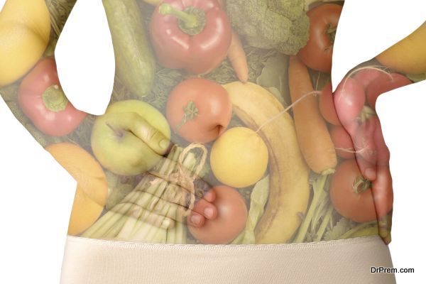 A woman's abdomen with fruits and vegetables isolated on white