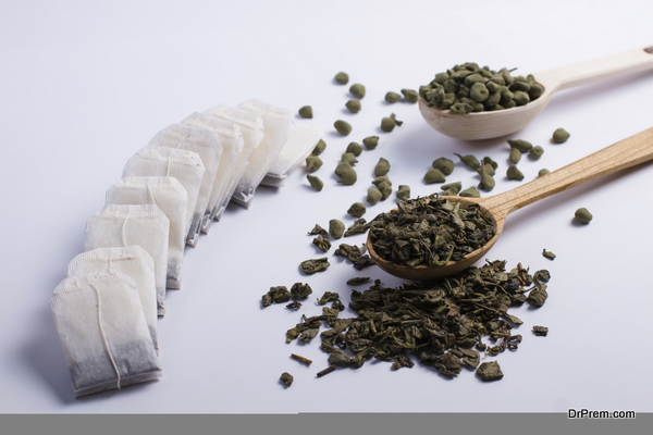 Different varieties of leaf tea in a wooden spoon and tea bags.