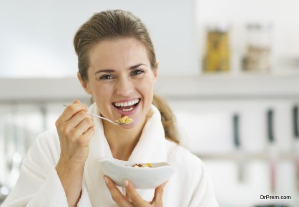 smiling young woman in bathrobe having healthy breakfast