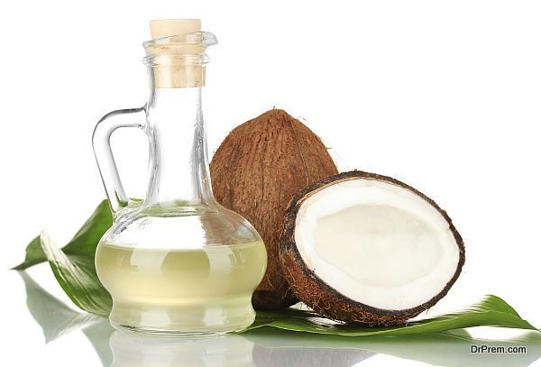 decanter with coconut oil and coconuts isolated on white