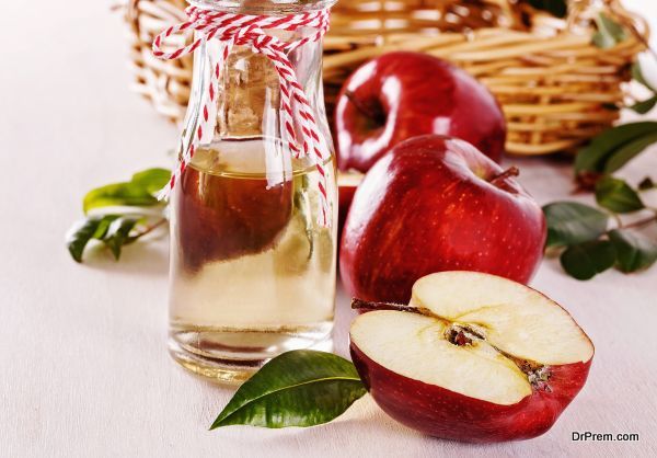 Apple cider vinegar and apples over white wooden background