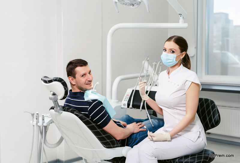 Dentist examining a patient's teeth in modern dentistry office. Doctor in disposable medical facial mask.