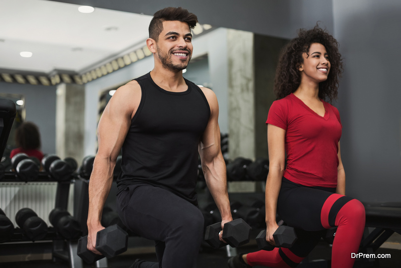 Diverse couple doing lunges with dumbbells in gym