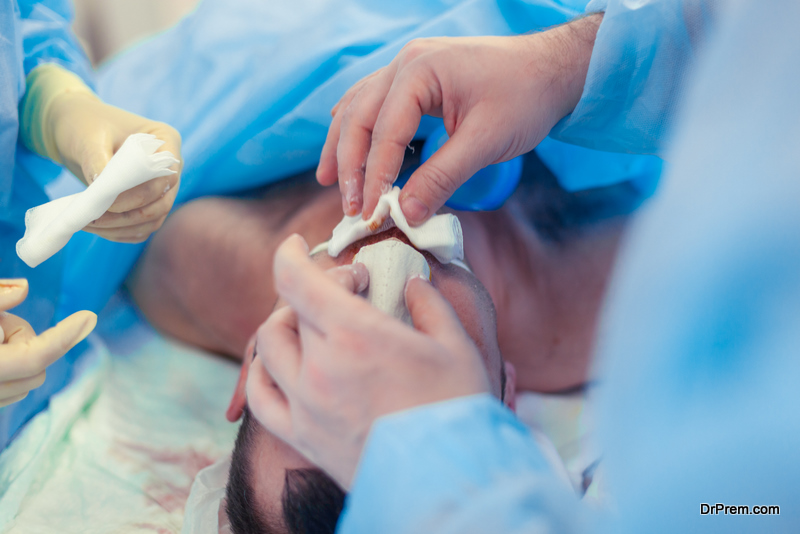 Surgeon and his assistant performing cosmetic surgery on nose in hospital operating room