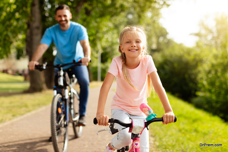 caucasian-father-and-girl-riding-bicycles-outdoors